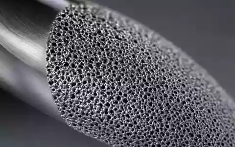 Zimmer Biomet US98956P1021 zeigt Makroaufnahme der porösen Titanoberfläche eines orthopädischen Implantats in dramatischem Streiflicht - Foto: THN