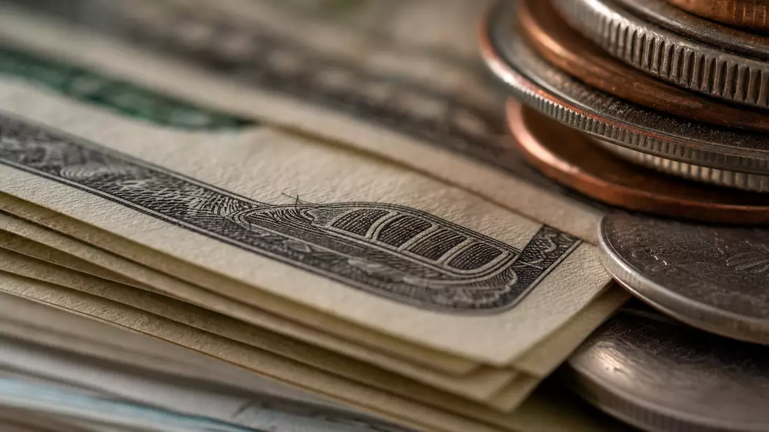 Makroaufnahme gestapelter Dollarnoten und Münzen mit Textur und weichem Licht