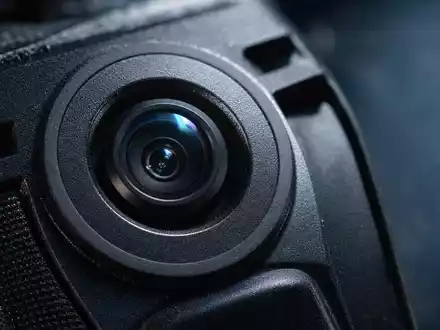 Axon Enterprise Inc. zeigt Makro-Detailaufnahme einer ungebrandeten Bodycam-Linse in extremer Nahaufnahme, US05464C1018 - Foto: THN