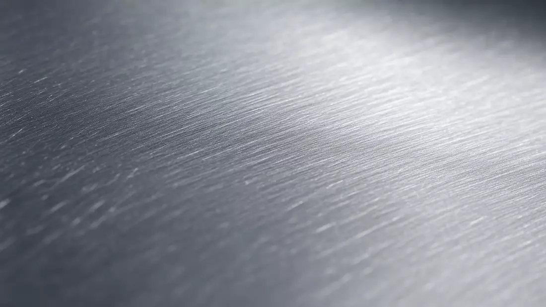 Extreme Makroaufnahme einer gebürsteten Aluminiumoberfläche mit metallischem Glanz und feiner Textur