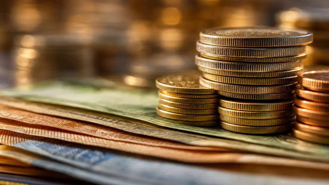 Makroaufnahme gestapelter Goldmünzen auf Banknoten mit Bokeh-Hintergrund