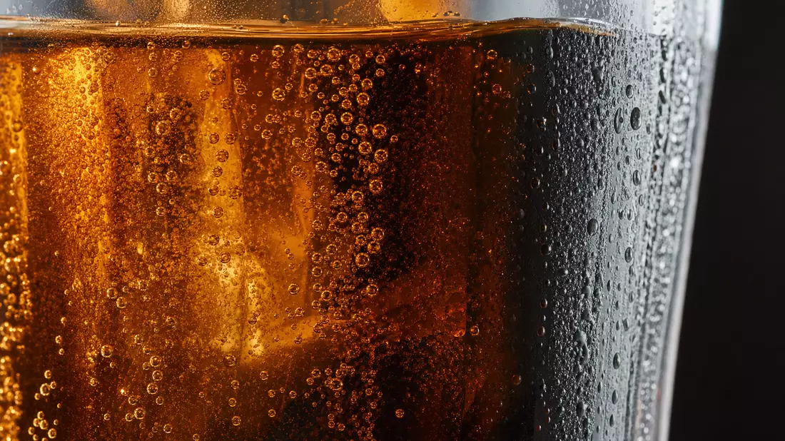 Extreme Makroaufnahme von Kohlensäurebläschen in einem unmarkierten Getränkeglas
