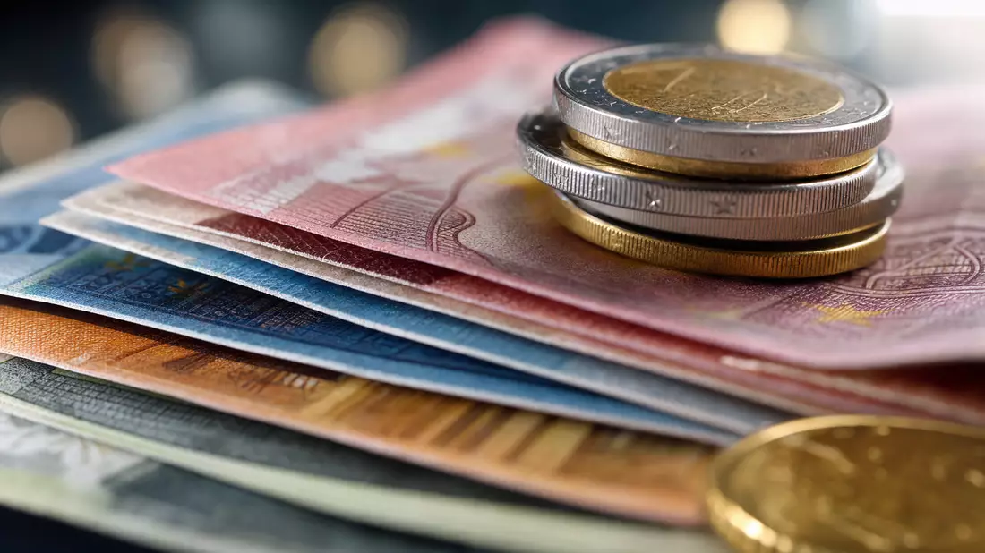 Makroaufnahme von Euro-Banknoten und gestapelten Münzen mit Bokeh