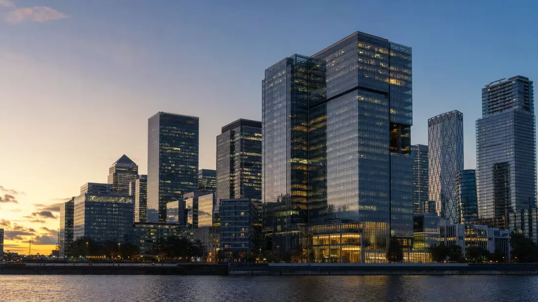 Glänzende Bankwolkenkratzer im Finanzviertel London bei Sonnenuntergang am Fluss