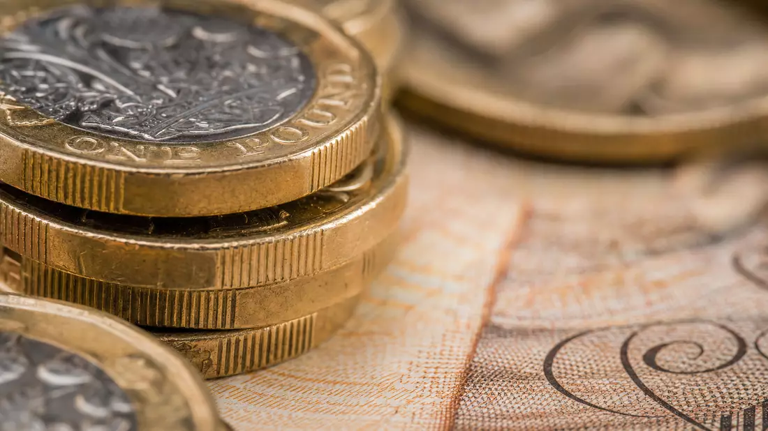 Makroaufnahme gestapelter britischer Pfundmünzen auf strukturierter Banknote