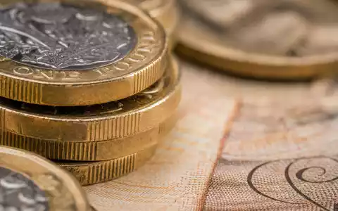 Barclays plc (ISIN GB0031348658) verwaltet Vermögenswerte, symbolisiert durch britische MĂŒnzen und Banknoten in Makroaufnahme - Foto: THN