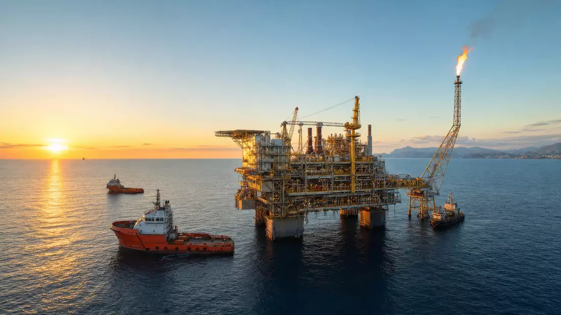 Offshore-Erdgasplattform im Mittelmeer bei Sonnenuntergang mit zwei Versorgungsschiffen