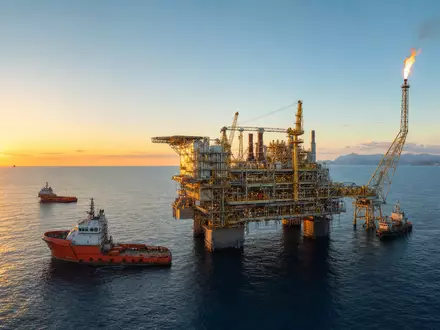 Energean plc GB00B753SF33 zeigt fotorealistisch eine Offshore-Gasplattform im Mittelmeer bei Sonnenuntergang mit Versorgungsschiffen - Foto: THN