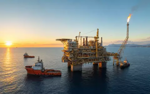Energean plc GB00B753SF33 zeigt fotorealistisch eine Offshore-Gasplattform im Mittelmeer bei Sonnenuntergang mit Versorgungsschiffen - Foto: THN