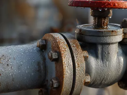 Energean plc GB00B753SF33 fokussiert Makroaufnahme eines verrosteten Gasrohrventils mit Kondenstropfen und Metallflanschen - Foto: THN
