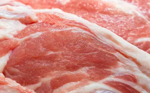 Cranswick plc GB0002333333 zeigt Makroaufnahme roher Schweinefleisch-Textur mit feiner Maserung und Feuchtigkeitstropfen - Foto: THN