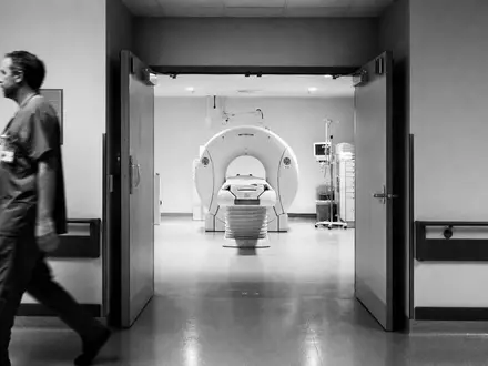 Siemens Healthineers DE000SHL1006 dokumentiert Schwarzweiß-Reportage mit Arzt und unmarkiertem CT-Scanner im Klinikflur - Foto: THN