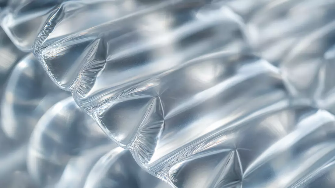 Extreme Nahaufnahme von transparenter Luftpolsterfolie mit Lichtreflexen in einzelnen Luftkammern