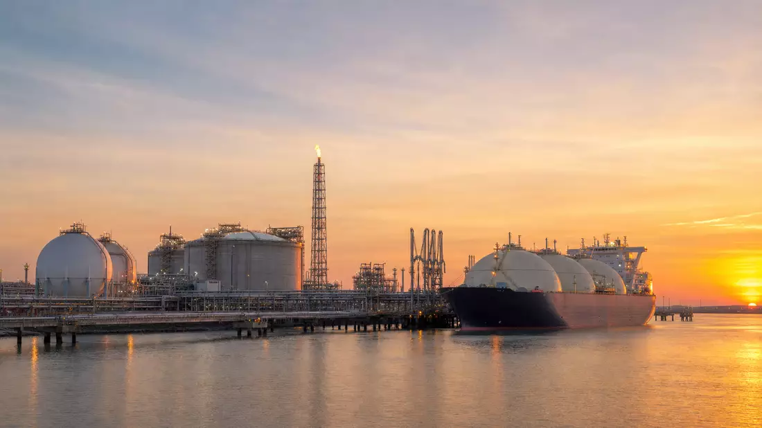 LNG-Terminal mit Tanker bei Sonnenuntergang, Speichertanks und Fackelturm
