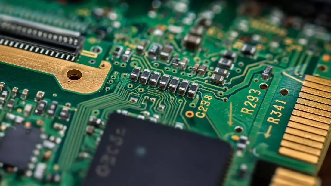 Extreme Makro-Nahaufnahme einer grünen Computerplatine mit goldenen Kupferleiterbahnen und Chips