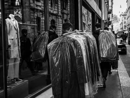 Hugo Boss AG DE000A1PHFF7 – Schwarzweißreportage zeigt Kleidungsträger in belebter europäischer Modeeinkaufsstraße - Foto: THN