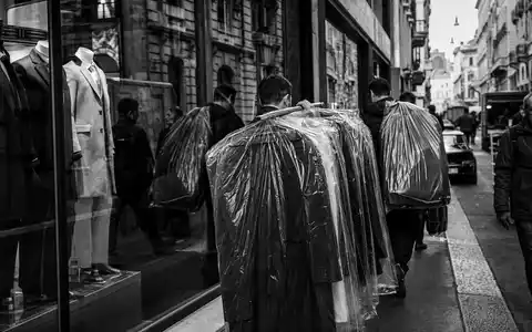 Hugo Boss AG DE000A1PHFF7 – Schwarzweißreportage zeigt Kleidungsträger in belebter europäischer Modeeinkaufsstraße - Foto: THN
