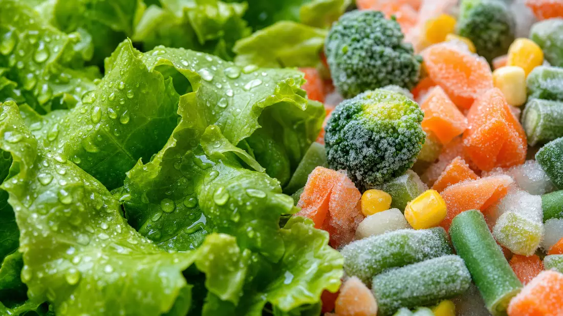 Makroaufnahme von frischem Salat und gefrorenem Gemüse mit Eiskristallen