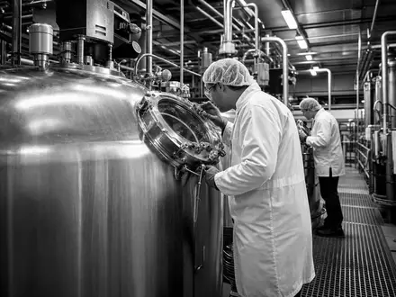 Dokumentarische Schwarzweiß-Aufnahme zeigt Mitarbeiter bei Corbion N.V. (ISIN NL0010583399) an Fermentationstanks im Werk - Foto: THN