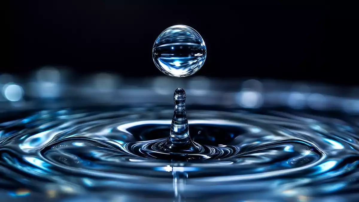 Makroaufnahme eines fallenden Wassertropfens mit Kronenspritzer auf dunklem Hintergrund