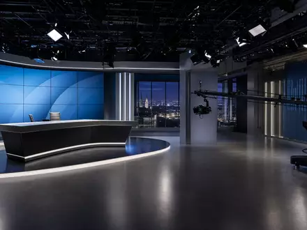 RTL Group LU0061462528 zeigt ein modernes TV-Studio mit Videowand, Kamerakran und Nachtskyline im Fenster - Foto: THN