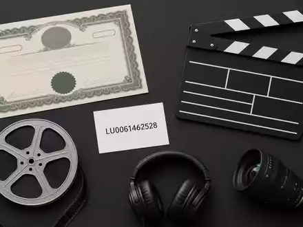 RTL Group LU0061462528 zeigt Flatlay mit Aktienzertifikat, ISIN-Karte, Klappe, Filmrolle und Kameraobjektiv - Foto: THN