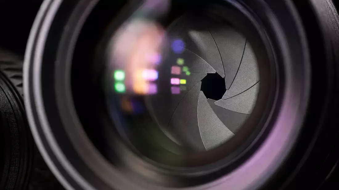 Makroaufnahme der Irisblende eines Kameraobjektivs mit farbigen Lichtreflexen