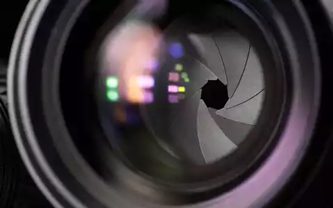 RTL Group LU0061462528 zeigt eine Makroaufnahme der Blendenlamellen eines Kameraobjektivs mit bunten Reflexionen - Foto: THN