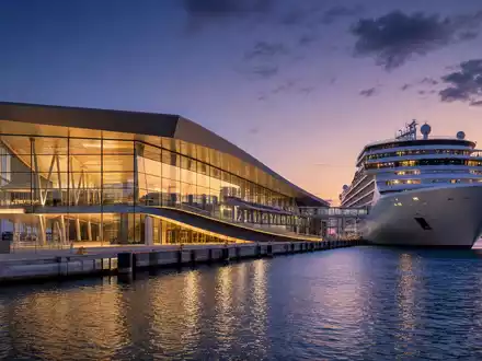 Architektur-Render eines modernen Kreuzfahrtterminals der Royal Caribbean Group, ISIN LR0008862868, abendliche DĂ€mmerung - Foto: THN