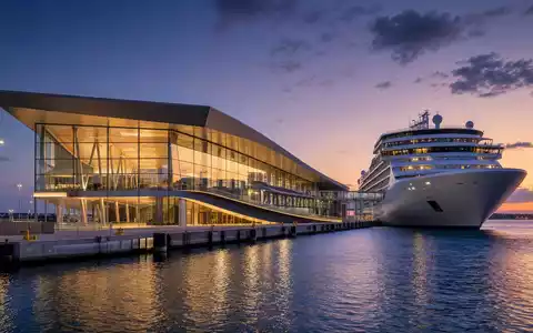 Architektur-Render eines modernen Kreuzfahrtterminals der Royal Caribbean Group, ISIN LR0008862868, abendliche Dämmerung - Foto: THN