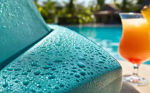 Makroaufnahme von Pool-Deck-Details der Royal Caribbean Group, ISIN LR0008862868, Wassertropfen und Cocktailglas - Foto: THN