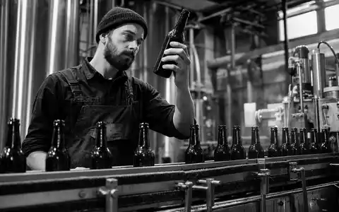 Constellation Brands Arbeiter kontrolliert Bierflaschen am Förderband in der modernen US21036P1084 Abfüllanlage - Foto: THN