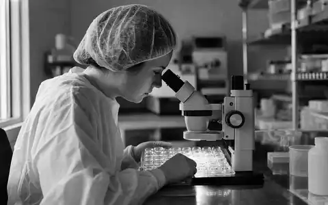 CooperCompanies US21664P1039 Schwarzweiß-Reportagefoto einer Wissenschaftlerin bei der Mikroskopinspektion von Kontaktlinsen-Gussformen im Labor - Foto: THN