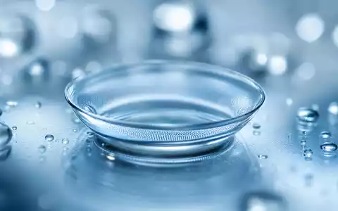 CooperCompanies Kontaktlinse US21664P1039 in extremer Makro-Detailaufnahme auf blauem Wassertropfen-Bokeh-Hintergrund mit klinischem Unterlicht - Foto: THN