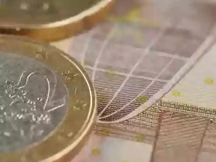 Makroaufnahme von MĂĽnzen und Banknotenstruktur, passend zum Finanzunternehmen KBC Group NV, ISIN BE0003565737 - Foto: THN