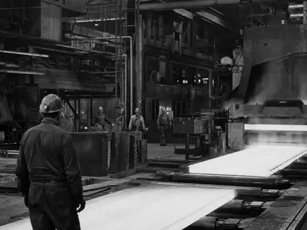 ArcelorMittal S.A. (LU1598757687) produziert Stahlbleche, diese dokumentarische Schwarzweißaufnahme zeigt Arbeiter an Walzanlagen - Foto: THN