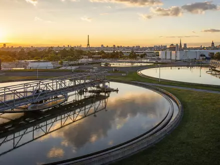 Veolia Environnement S.A. (FR0000124141) zeigt fotorealistisch eine moderne Wasseraufbereitungsanlage bei Sonnenuntergang nahe einer Großstadt Frankreichs - Foto: THN