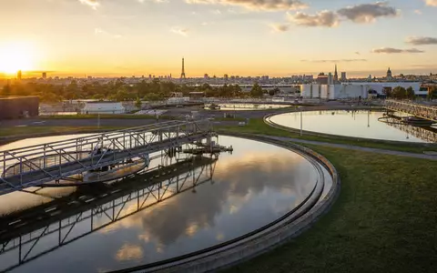 Veolia Environnement S.A. (FR0000124141) zeigt fotorealistisch eine moderne Wasseraufbereitungsanlage bei Sonnenuntergang nahe einer Großstadt Frankreichs - Foto: THN