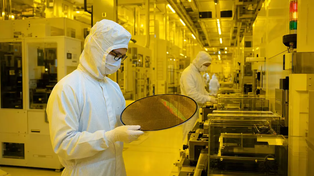Techniker im Reinraum inspiziert Siliziumwafer in Halbleiterfabrik