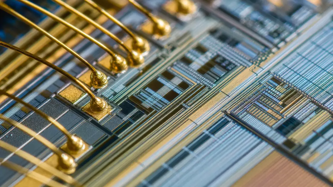 Makroaufnahme einer Mikrochip-Oberfläche mit goldenen Bonddrähten