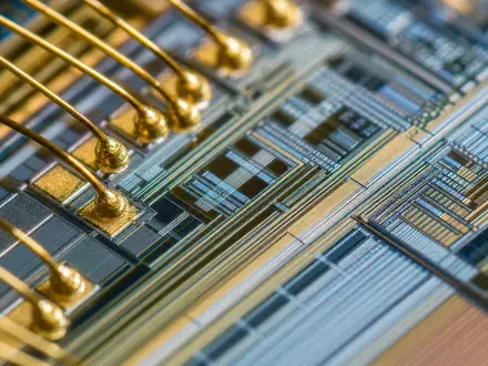 Infineon Technologies AG (DE0006231004) entwickelt Mikrochips, hier als eindrucksvolle Makroaufnahme einer Chip-Oberfläche mit Bonddrähten gezeigt - Foto: THN