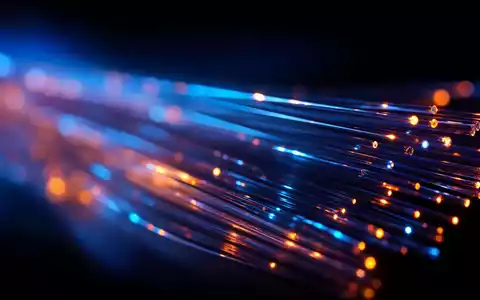 BT Group plc (ISIN GB0030913577) zeigt eine Makroaufnahme leuchtender GlasfaserstrÀnge mit blauen und orangen Lichtimpulsen - Foto: THN