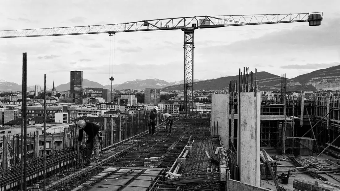 Schwarzweisse Dokumentarfotografie einer Hochbaustelle mit Kran und Arbeitern