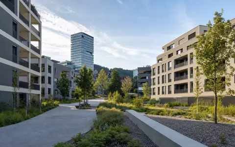 Allreal Holding AG (CH0008837566) zeigt fotorealistisch moderne Schweizer Wohnüberbauung mit Grünanlagen und Hochhaus im Hintergrund - Foto: THN