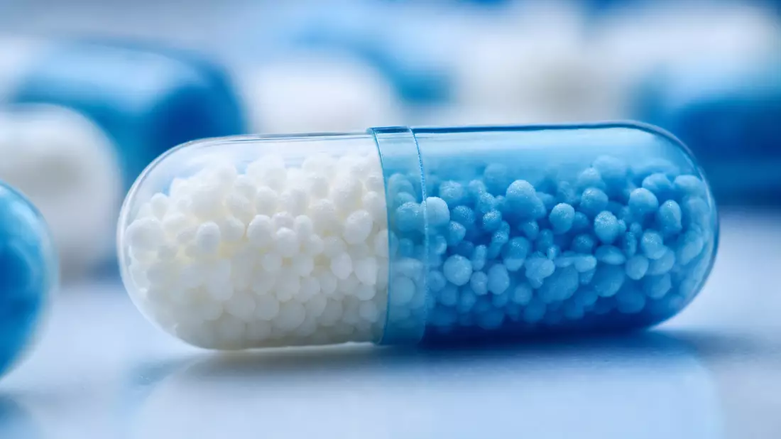 Extreme Makrofotografie einer Pharmakapsel mit blauem und weißem Granulat