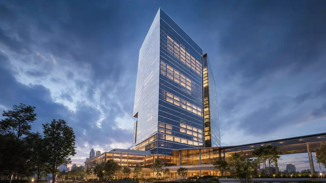 CGI-Render eines gläsernen Bankhochhauses bei Abendbeleuchtung mit dramatischem Wolkenhimmel