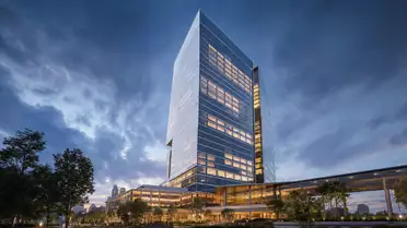 CGI-Render eines gläsernen Bankhochhauses bei Abendbeleuchtung mit dramatischem Wolkenhimmel