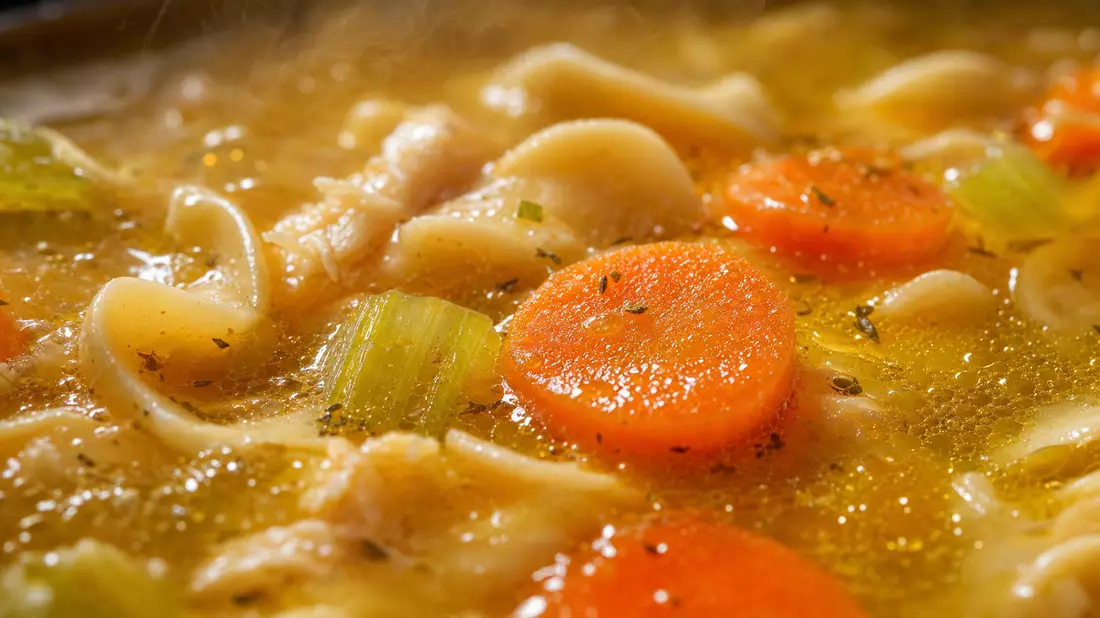Extreme Makro-Detailaufnahme einer Hühnersuppe mit Nudeln und Gemüse