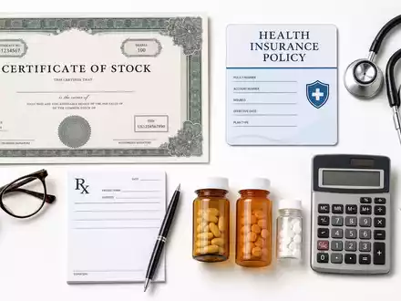Cigna Group Flatlay mit Aktienzertifikat ISIN US1255231003, Stethoskop, Versicherungspolice und Medikamentenfläschchen auf weißem Untergrund - Foto: THN