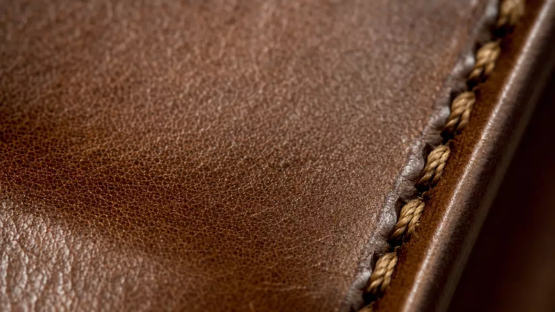Makroaufnahme von braunem Leder mit sichtbarer Naht und Textur im Studiolicht